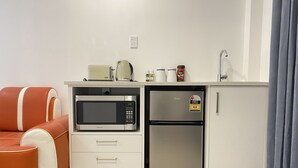 Una kitchenette compacta con microondas, refrigerador y una pequeña encimera.