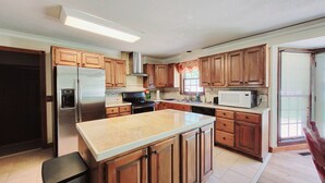 A modern kitchen with wooden cabinets, stainless steel appliances, and a large island. - Entire 5 Bedroom Home in Golf Community - 12 Beds - ASK ABOUT DISCOUNT (Fort Wayne)