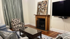 Un salon doté d’une cheminée, d’un téléviseur fixé au mur et de meubles à motifs.