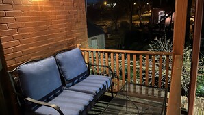 Un balcon avec une table en métal et un banc bleu doté d’un coussin.