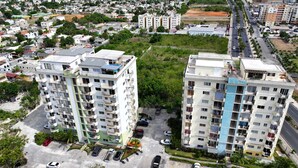 Um edifício residencial alto com várias varandas, estacionamento e vista do bairro ao redor.