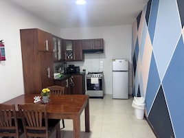 Una cocina compacta con armarios de madera, una estufa a gas, un microondas y un refrigerador.