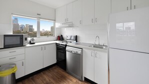 Una cocina moderna con gabinetes blancos, electrodomésticos de acero inoxidable y un ventanal con vista a la ciudad.