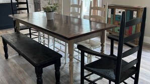 A dining area with a wooden table and chairs, a chandelier, and a painting of a beach scene. - Anchors Aweigh (Cape Charles)