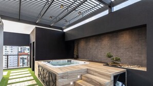 A modern outdoor hot tub area with a wooden deck, steps, and a small garden with a bonsai tree. - Modern apartment in Quito (Quito)