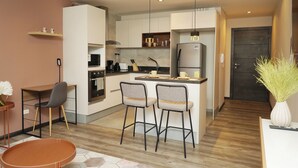 A modern kitchen with a central island, bar stools, a dining table, and a coffee machine. - Modern apartment in Quito (Quito)