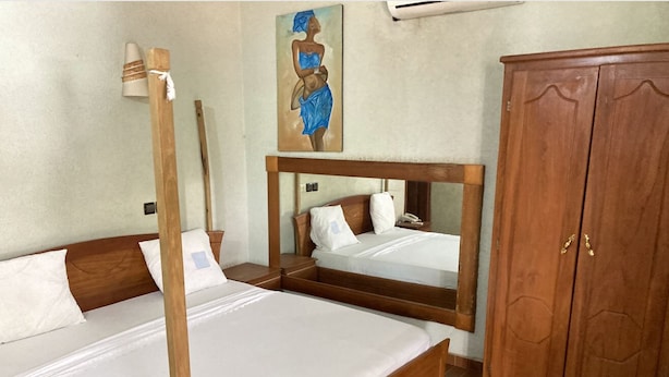 Una habitació amb dos llits de fusta, un armari de fusta i un quadre a la paret.
