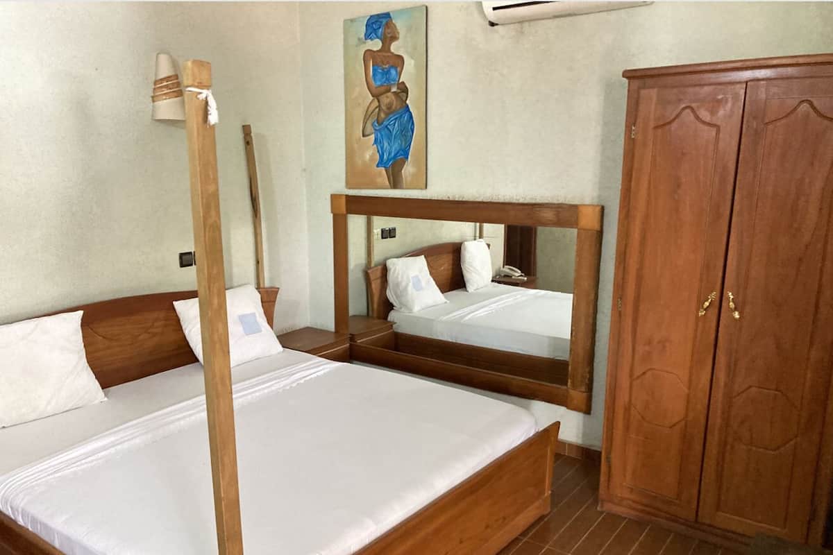 Una habitación con dos camas de madera, un armario de madera y un cuadro en la pared.