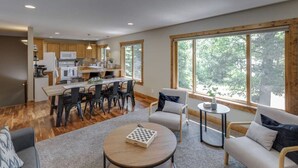 A spacious living area with a dining table, sofas, and a view of the outdoors through large windows. - Private Escape on Fishermans Way (Merrifield)
