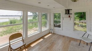 A room with large windows overlooking a body of water, a wooden deck, and a bench. - Private Escape on Fishermans Way (Merrifield)