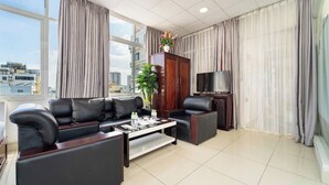A modern living room with a sofa set, a coffee table, a TV stand, and a large window with curtains.
