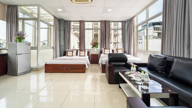 A hotel room with a bed, a sofa, a coffee table, a desk, and a refrigerator.