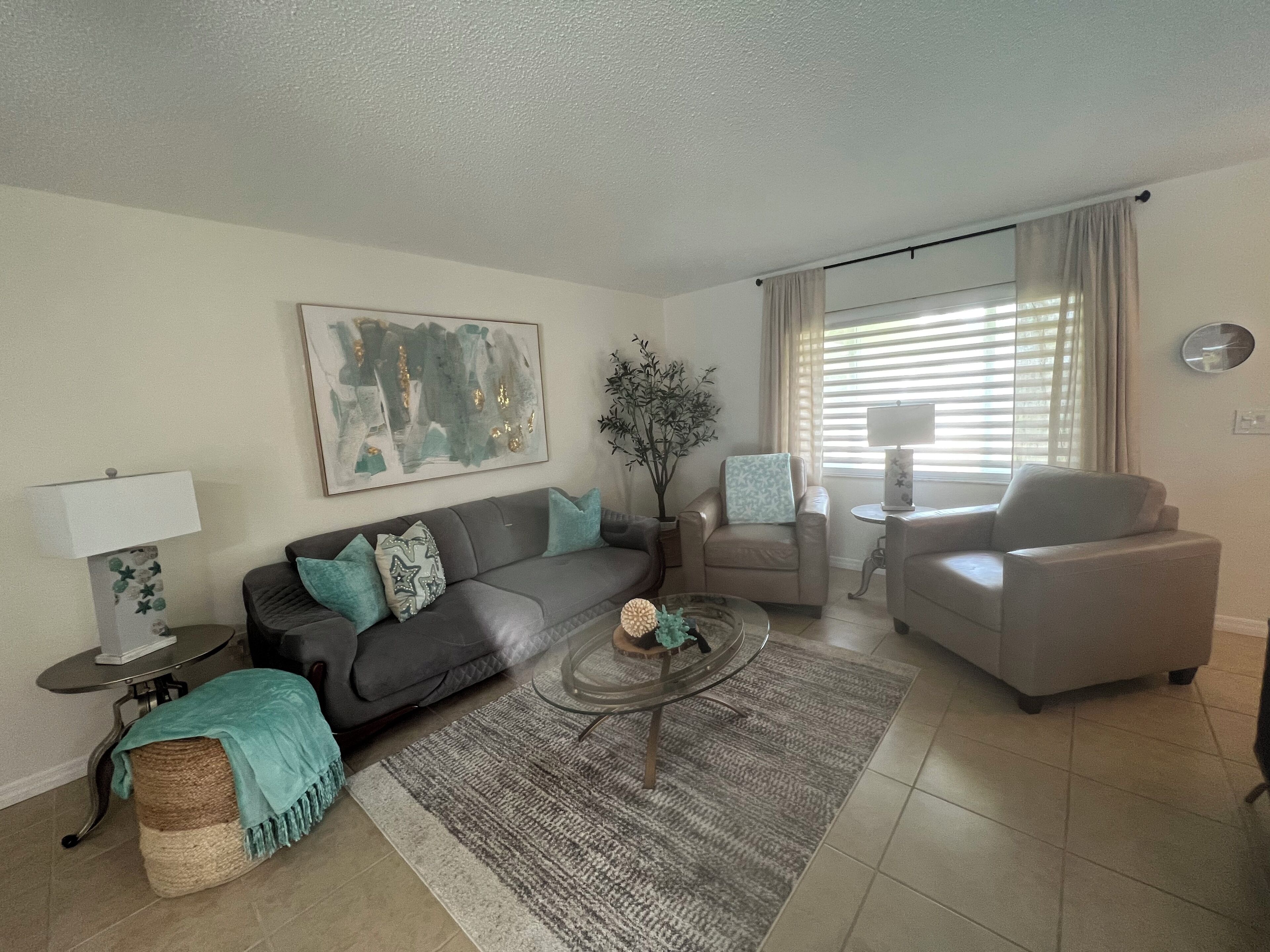 A living room with a grey sofa, a round coffee table, a beige armchair, and a small side table with a lamp.