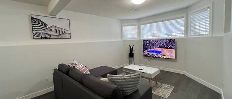 Una sala de estar moderna con un sofá gris, un televisor de pantalla plana y un cuadro en la pared.