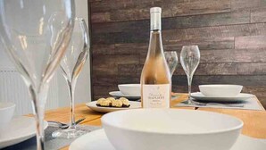 Una mesa vestida con platos blancos, una botella de vino y copas de vino vacías.