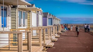 Una hilera de cabañas de madera en la playa, con una pasarela de madera que las conecta.