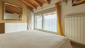 Ein Schlafzimmer mit einem großen Bett, einem Schminktisch, einem Fenster mit Ausblick und einer Heizung.