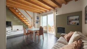 Ein modernes Wohnzimmer mit einer Holztreppe, einem Essbereich und einem gemütlichen Sofa.