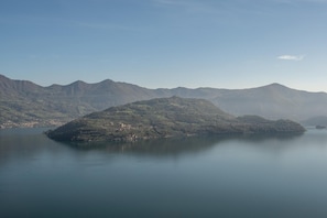 A mountainous landscape with a body of water in the foreground and a town on the hills.