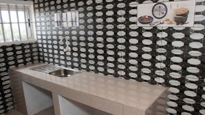 A kitchen with a sink, a window, and a tiled backsplash. - Alafia Hotel Ketou (Kétou)