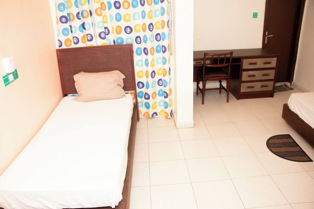 A hotel room with a bed, a desk, and a chair.