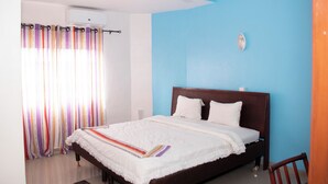 A bedroom with a bed, a ceiling fan, a window with curtains, and a wall-mounted air conditioner. - Alafia Hotel Ketou (Kétou)