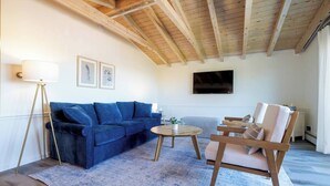 Un salon avec un canapé bleu, une table basse en bois et une chaise en bois.
