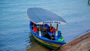 Un bote con toldo que dice 'KIGUFI HILL' amarrado en una orilla arenosa.