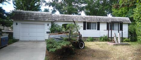A single-story house with a garage, surrounded by trees and a yard.