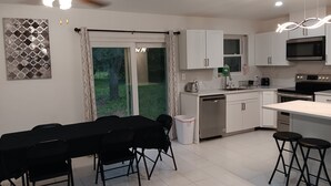 Una cocina moderna con armarios blancos, encimera negra y un ventilador de techo.