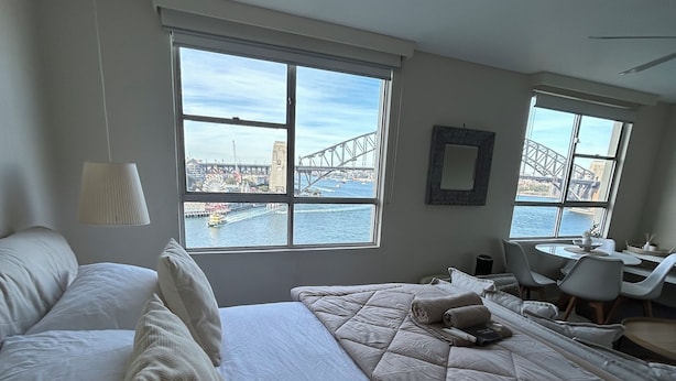 Une chambre d’hôtel avec un grand lit, un bureau et une vue sur un pont et sur l’eau.