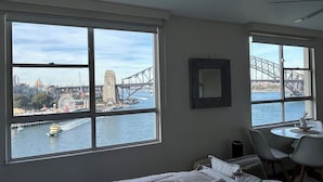 Une chambre d’hôtel dotée de grandes fenêtres donnant sur un pont et sur le paysage urbain.