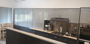 Eine moderne Küche mit grauen Schränken, einem eingebauten Herd, einer Kaffeemaschine und einem Backofen.