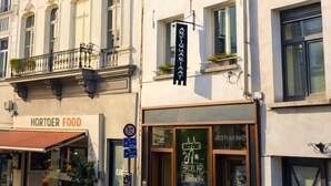 Un immeuble à plusieurs étages dont la devanture porte l’inscription « HORTOER FOOD » et qui affiche une enseigne « GROPLAB » avec un symbole de vélo.