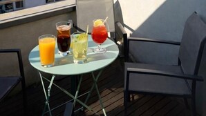 Une terrasse sur le toit, avec une table dressée pour prendre un verre, une chaise et une vue sur le clocher d’une église historique.