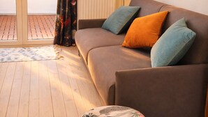 Un canapé marron agrémenté de coussins turquoise et orange, un coussin décoratif à motifs et un plancher en bois.