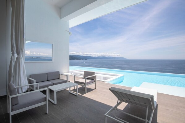 A modern balcony with a pool, white furniture, and a scenic ocean view. - 2Bd 2Baths Oceanfront - Orchid Unit 7E 2BD Condo for rent in Conchas Chinas, Pue (Puerto Vallarta)