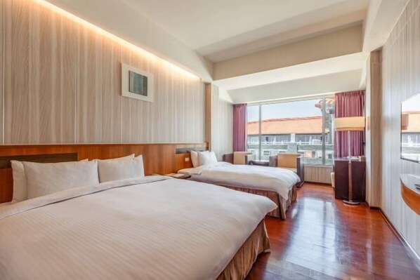 Une chambre d’hôtel avec deux lits, une tête de lit en bois, une grande fenêtre avec des rideaux et une vue sur le paysage urbain.