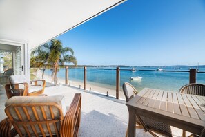 Un balcon agrémenté de meubles en osier, avec vue sur la mer et des bateaux à l’horizon.