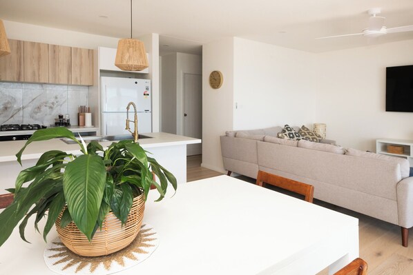 A modern kitchen with a white countertop, a built-in stove, and a refrigerator. There is a wicker basket with green leaves on the countertop. - "ON THE BEACH" with million-dollar views. Enjoy the best beach at the Bay. (Corlette)