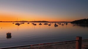 Un rivage paisible, avec des bateaux amarrés sur l’eau, une plage de sable au premier plan et un ciel dégagé.