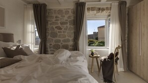 Un dormitorio con una cama grande, pared de piedra y vistas a la ciudad.