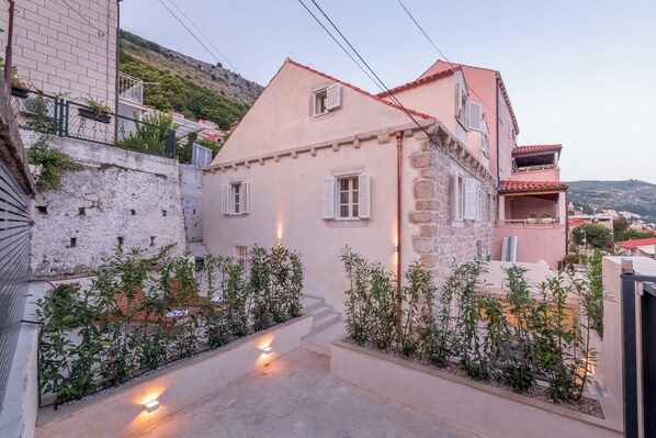 A traditional stone building with a sloped roof, a small balcony, and a staircase leading to the entrance. - Villa Miri, superior heritage villa with swimming pool (Dubrovnik)