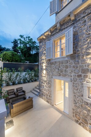 A stone building with a balcony, outdoor seating, and a door leading to an interior space. - Villa Miri, superior heritage villa with swimming pool (Dubrovnik)
