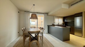 Una cucina moderna con isola centrale, zona pranzo con tavolo e sedie, e un'ampia finestra con tende.