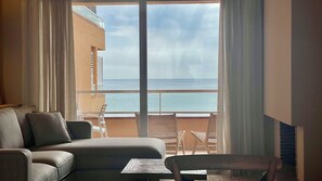 A room with a balcony, a sofa, two chairs, and a table.
