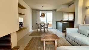 Un salon moderne comprenant un canapé, une table à manger avec des chaises, un coin cuisine et une grande fenêtre avec des rideaux.