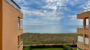 A view of the sea from a building with balconies overlooking a grassy area.