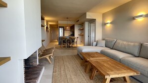 Ein modernes Wohnzimmer mit einer Couch, Holztischen und einem Essbereich mit Stühlen.