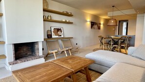 Ein Wohnzimmer mit Kamin, Holzmöbeln, einer Couch und einem Essbereich mit Stühlen und einem Tisch.